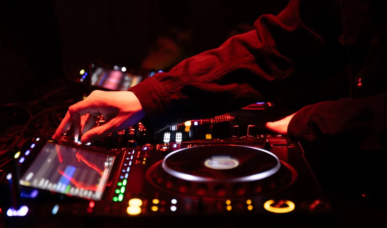 A DJ skillfully adjusting the sound mixer during an energetic concert, creating a vibrant musical experience.